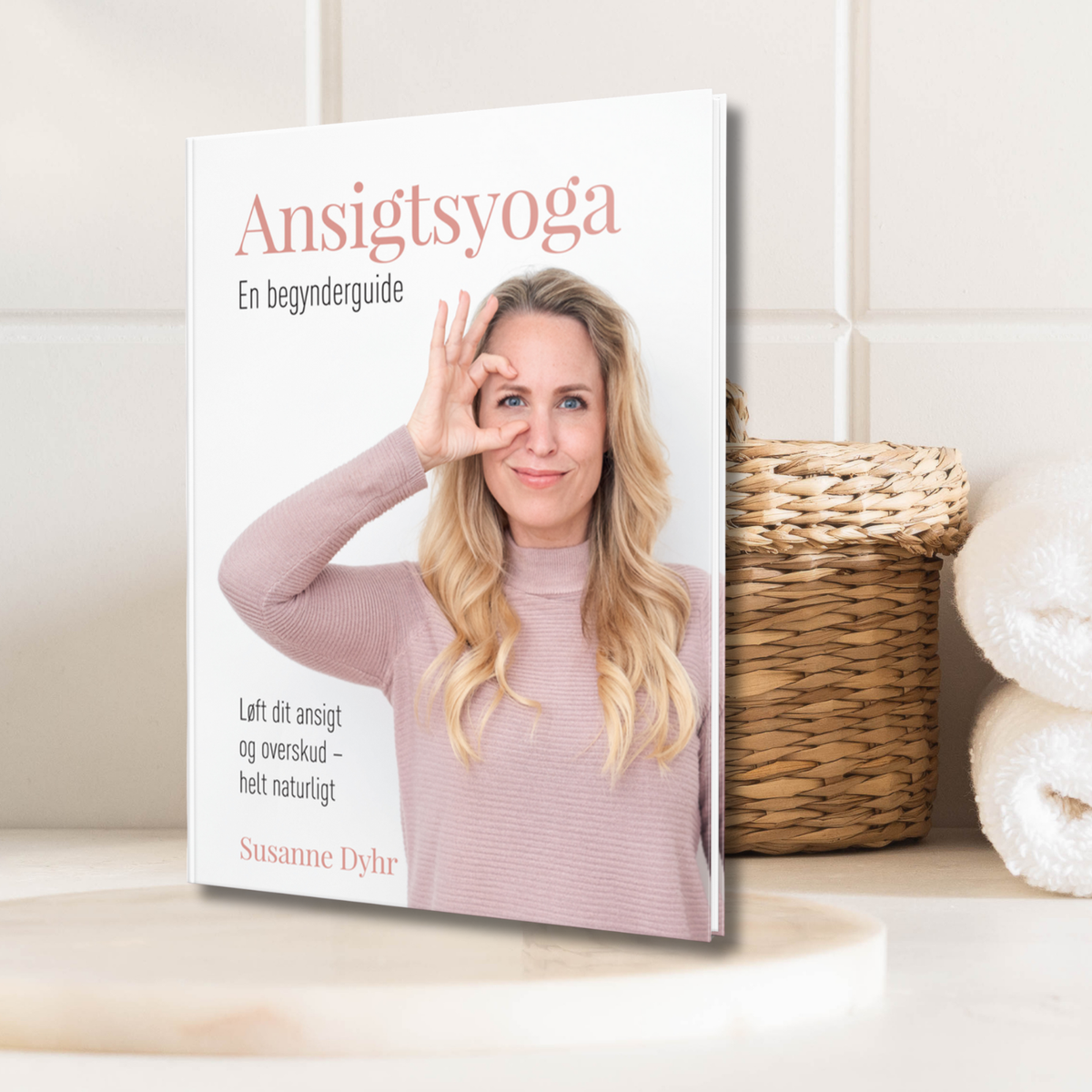 Bogen Ansigtsyoga - En begynderguide af Susanne Dyhr i et lyst badeværelsesmiljø